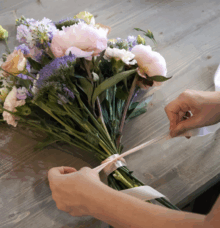 En bukett med blommor binds med ett band på ett bord.